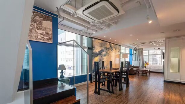A modern interior with a staircase, wooden flooring, a dining area, and a large abstract painting on the wall. - Tung Nam Lou Art Hotel (Kowloon)