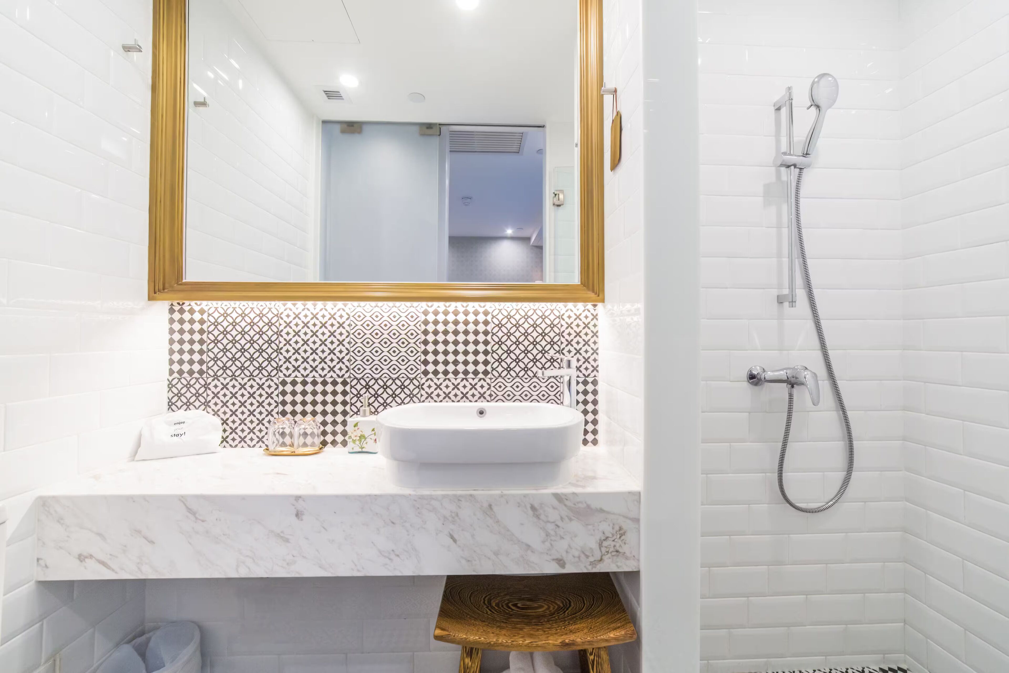 A bathroom with a white sink, a mirror with a gold frame, and a shower with a handheld showerhead.