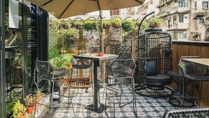 An outdoor patio with a patterned floor, metal chairs, a table, and a birdcage. - Tung Nam Lou Art Hotel (Kowloon)