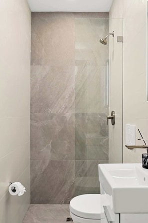 A bathroom with a shower, toilet, and sink.
