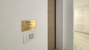 A hallway with a door, a wall-mounted light switch, and a plaque with text. - Eur Home Clusone (Clusone)