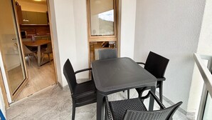 A balcony with a table and chairs, a view through a window, and a kitchen area visible through an open door. - Eur Home Clusone (Clusone)