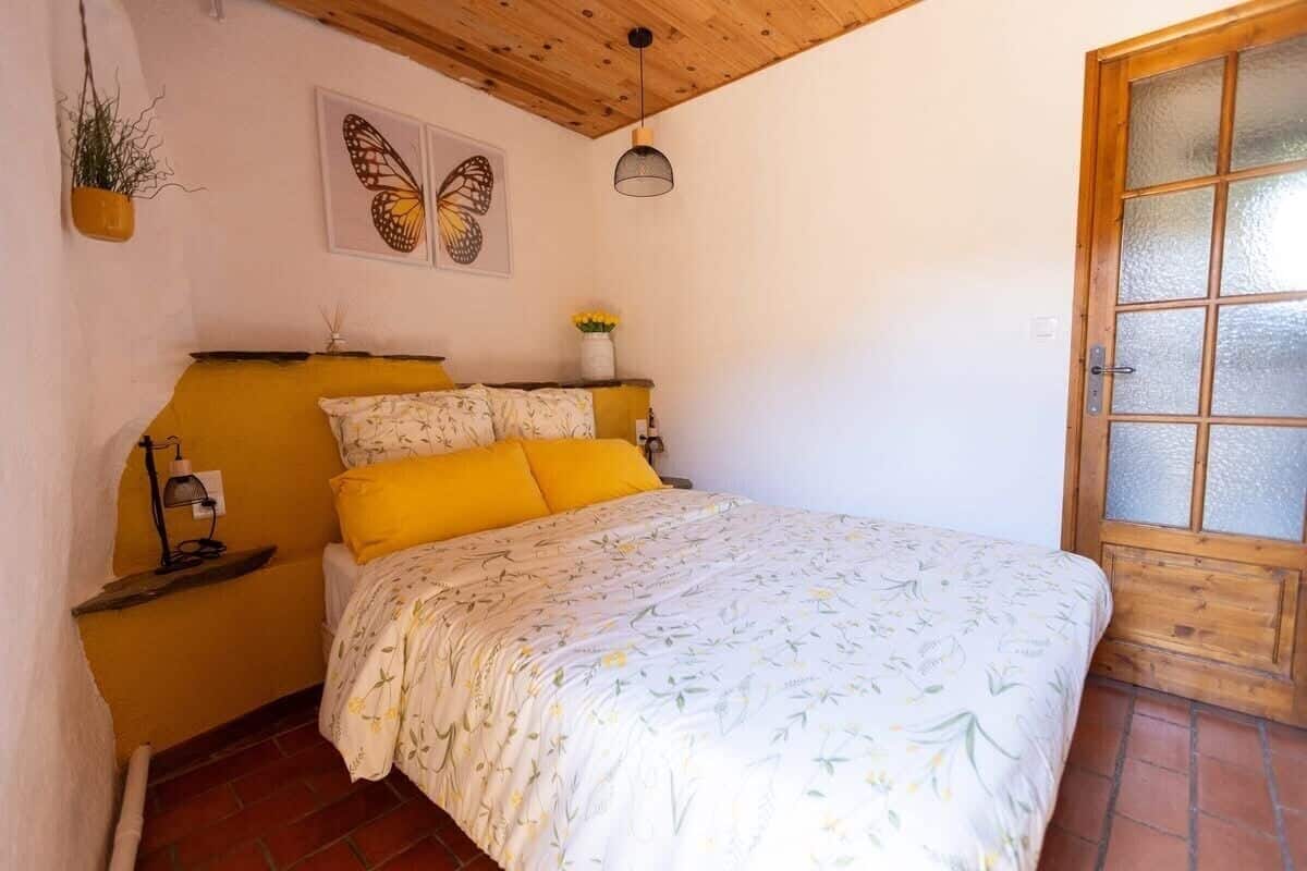 A bedroom with a bed, a nightstand, a wall-mounted plant, and a door with frosted glass panels.
