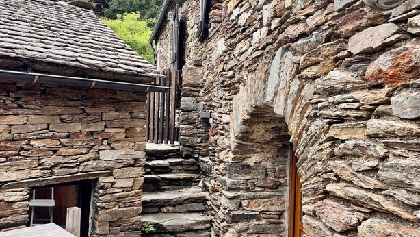 Un edificio de piedra con una puerta de madera y una pequeña mesa afuera.