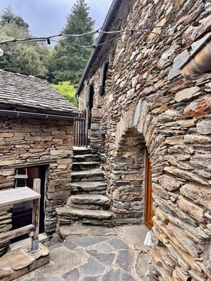 Un edificio de piedra con una puerta de madera y una pequeña mesa afuera.
