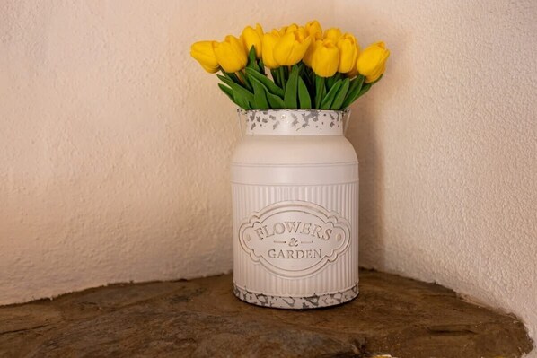 A white ceramic vase with a floral pattern and the words "Flowers & Garden" on it, containing yellow tulips.