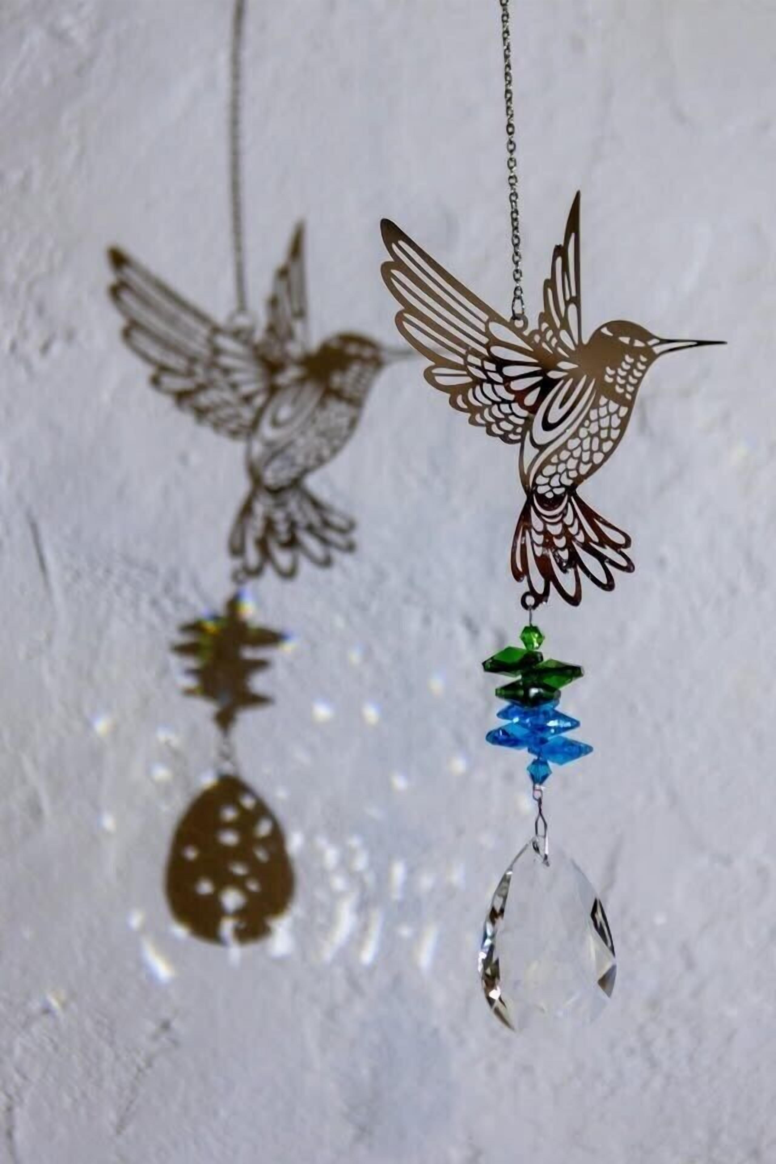 Two hanging bird-shaped pendants with a clear crystal and a green bead.