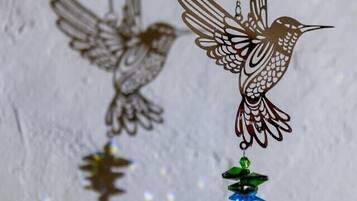 Two hanging bird-shaped pendants with a clear crystal and a green bead.