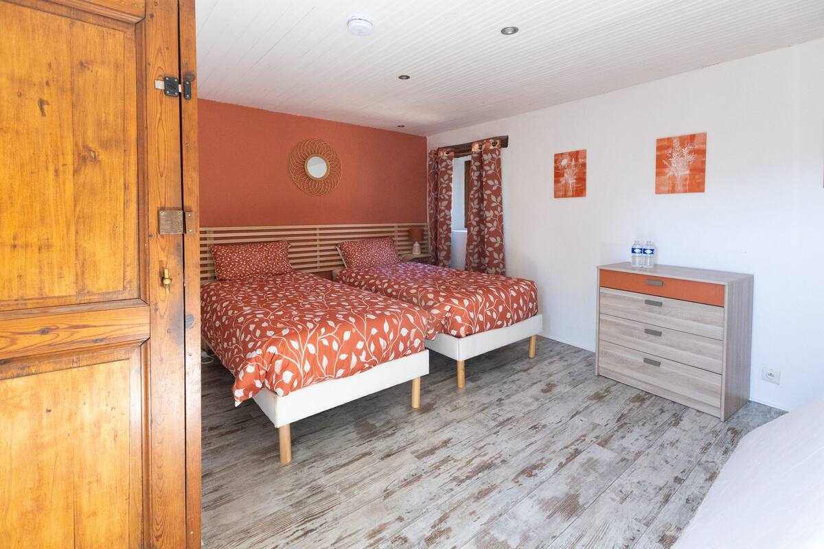 A bedroom with two beds, a wooden wardrobe, a dresser, and a mirror.