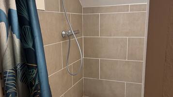 Un pequeño espacio de ducha con azulejos, con cabezal de ducha y manguera.