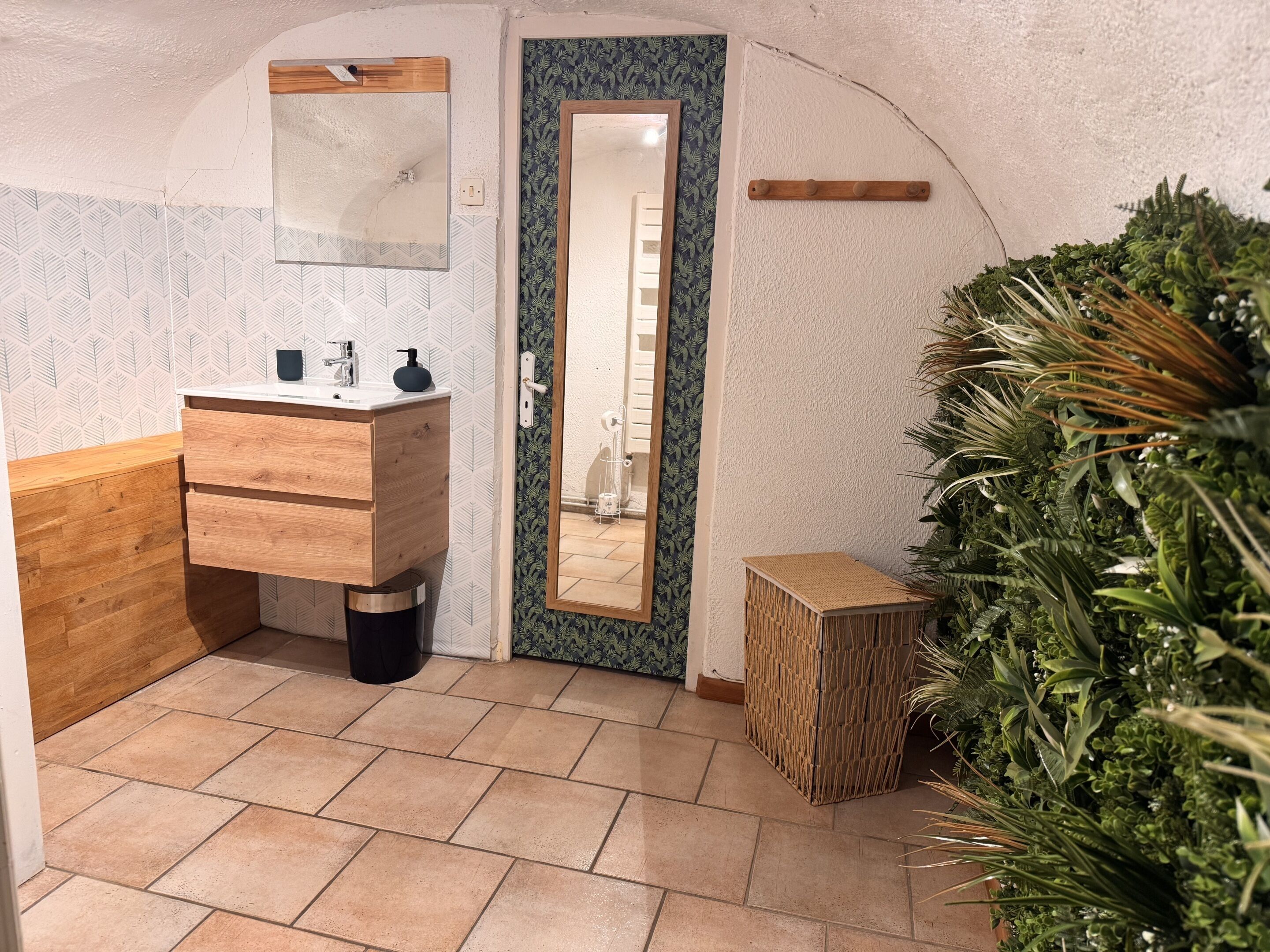 A compact bathroom with a wooden vanity, a mirror, and a small plant.