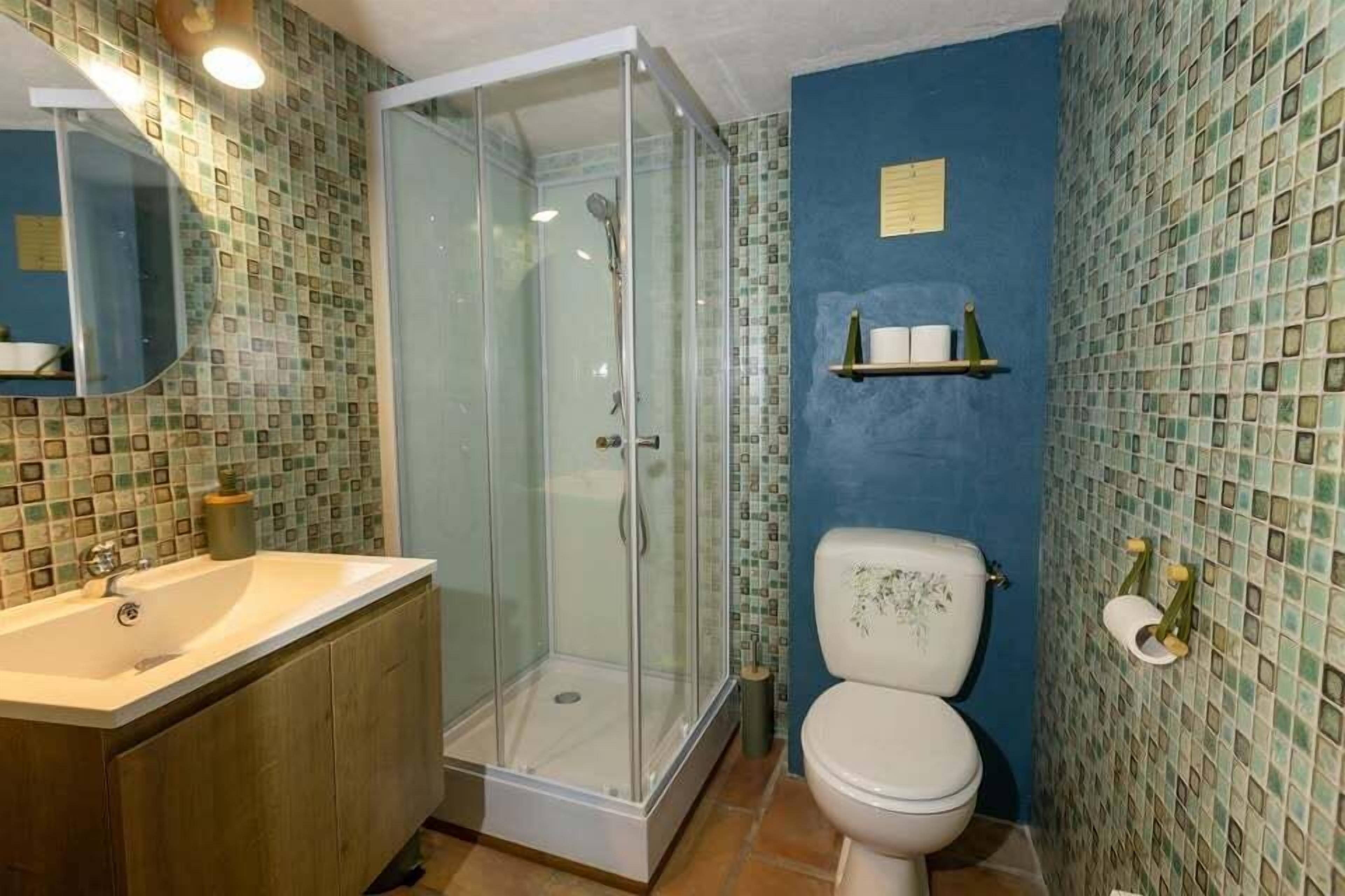 A bathroom with a glass-enclosed shower, a white sink, and a toilet.