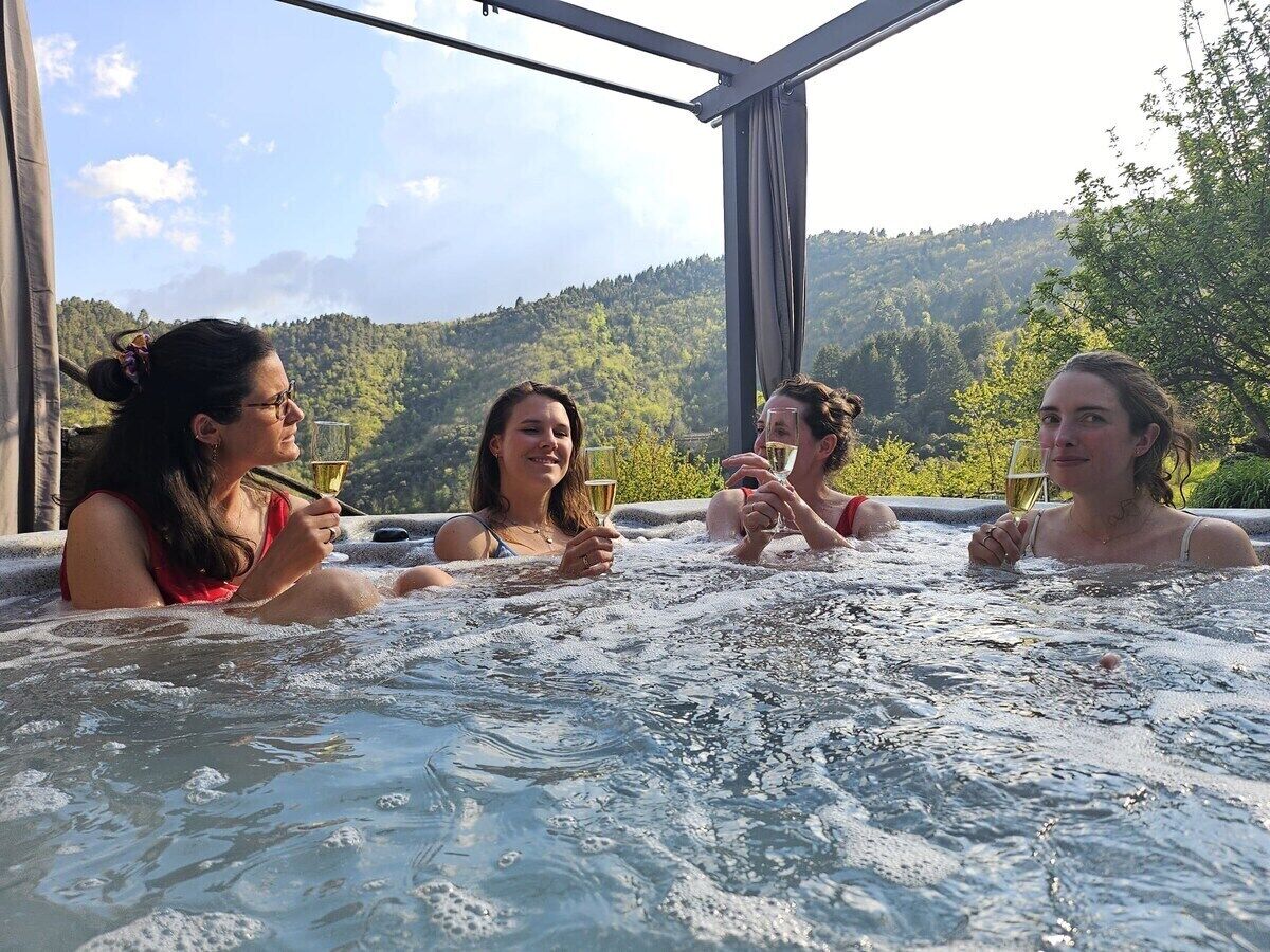 A group of people in a hot tub with a mountainous landscape in the background.