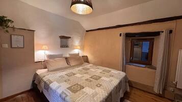 A bedroom with a bed, two bedside lamps, a window with curtains, and a ceiling light fixture.