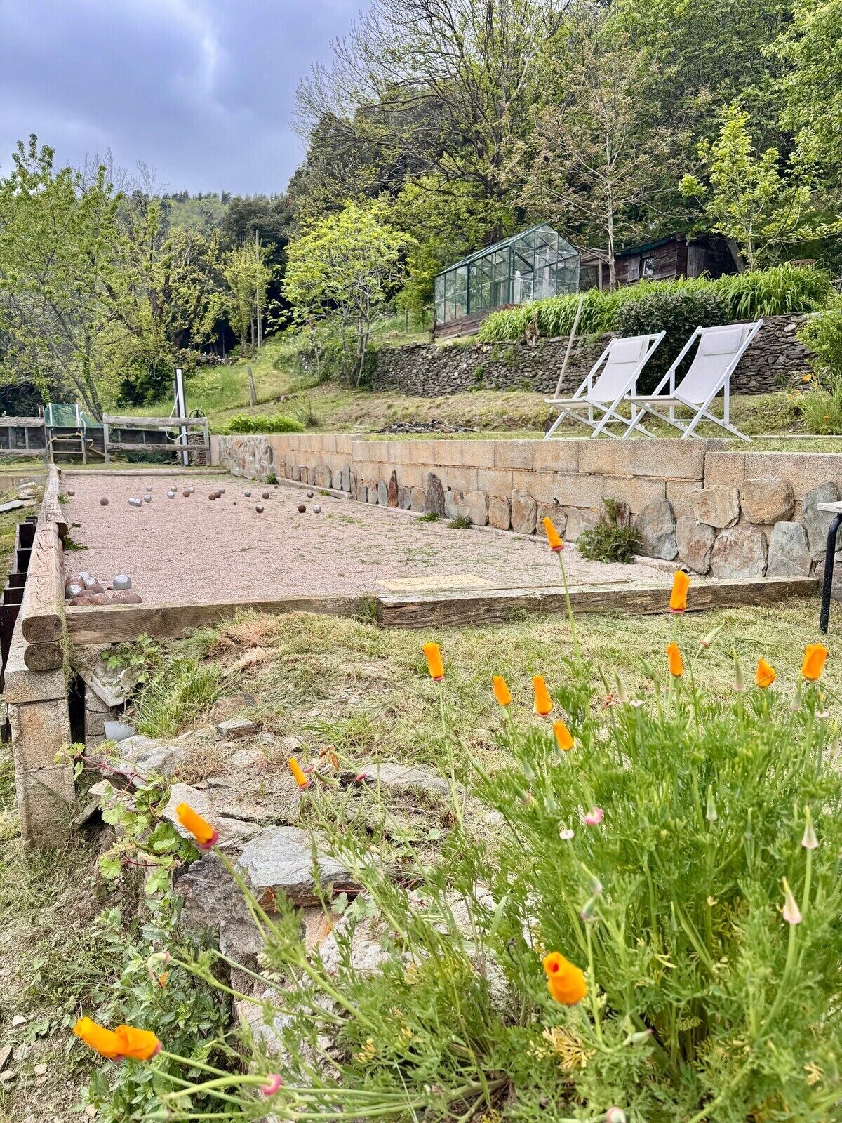 A garden area with a stone pathway, a small pond, and a seating area with chairs.
