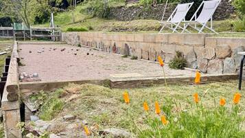 A garden area with a stone pathway, a small pond, and a seating area with chairs.