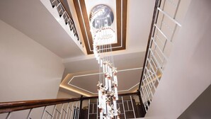 Un interior de varios niveles con una escalera, una lámpara decorativa y el logotipo de Costa Vista Beach Resort.