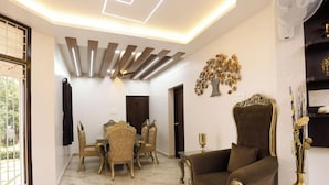Un salón amplio con juego de comedor, un sillón grande y un jarrón decorativo.