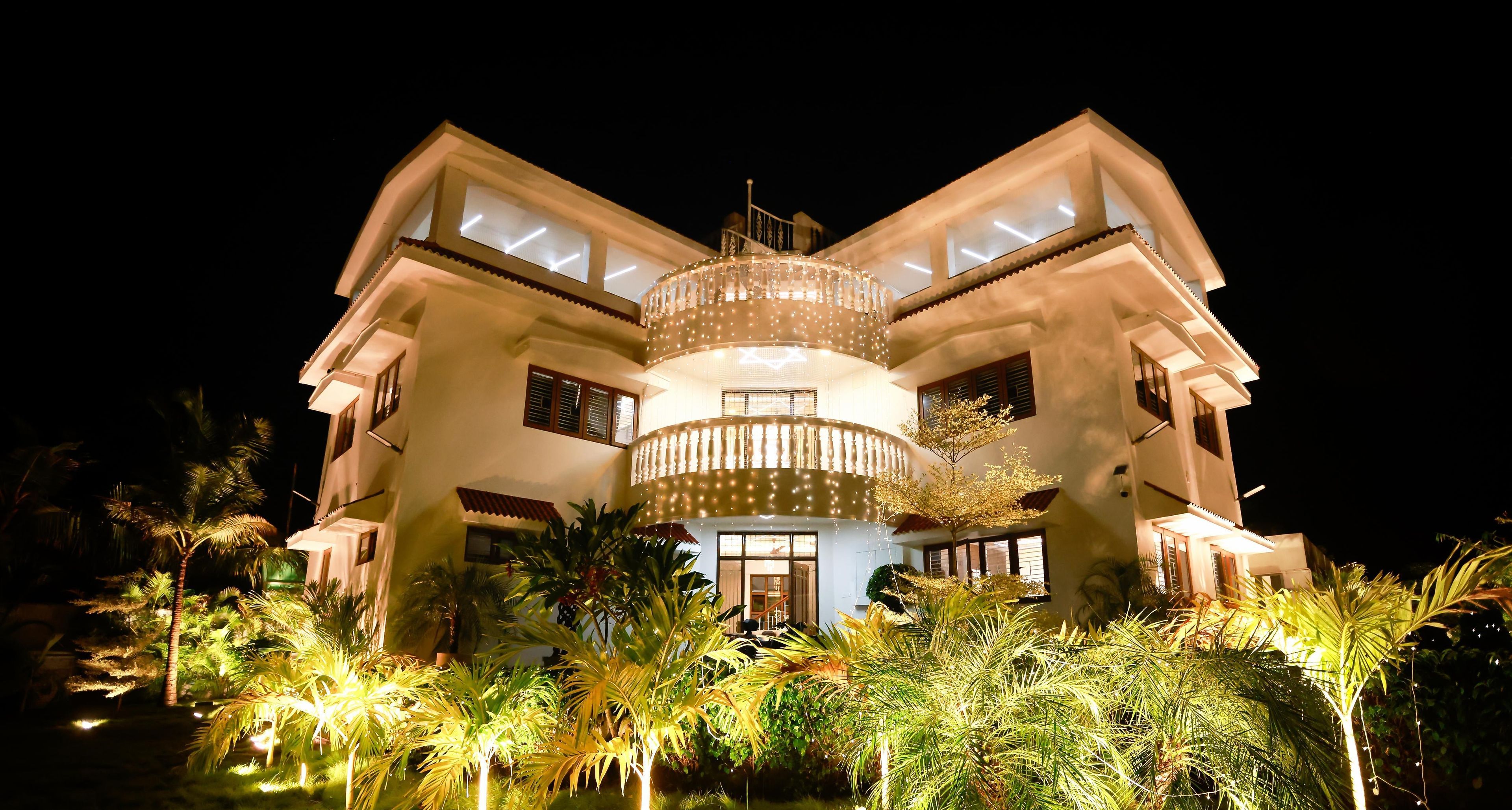 A multi-story building with a central circular balcony, surrounded by lush greenery and palm trees.