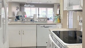 Eine Küche mit weißen Schränken, einem Geschirrspüler, einem Backofen und einer Mikrowelle.