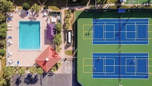 Eine Luftaufnahme eines Anwesens mit Schwimmbad, Tennisplätzen und einer überdachten Sitzgelegenheit.