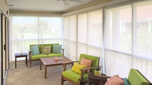 Ein Wintergarten mit einem grünen Sofa, einem Holztisch und einem Sessel.