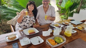 A dining table with breakfast items including toast, eggs, sausage, and fruit. - 64 ZENJ HOUSE (Zanzibar Town)