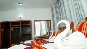 A hotel room with a bed, a wardrobe, a mirror, and a swan decoration. - 64 ZENJ HOUSE (Zanzibar Town)