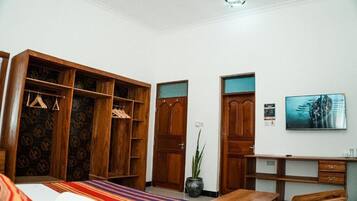 Ein Hotelzimmer mit Bett, Schreibtisch, Kleiderschrank und einer Zimmerpflanze.
