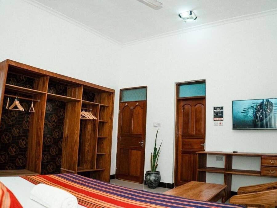 Ein Hotelzimmer mit Bett, Schreibtisch, Kleiderschrank und einer Zimmerpflanze.
