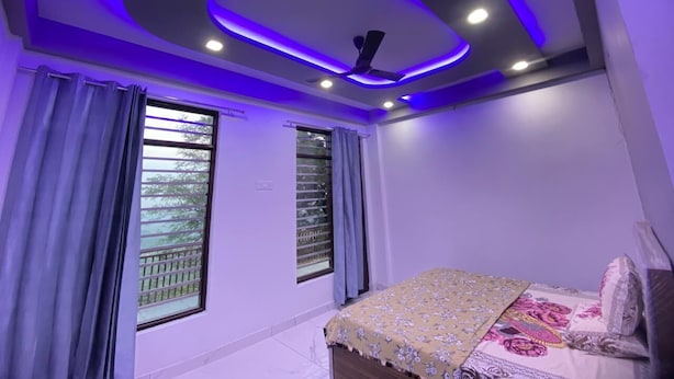 A bedroom with a bed, a ceiling fan, and a window with curtains. - Revanta Home Stay (Naina Devi)