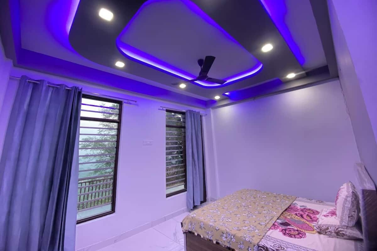 Un dormitorio con cama, ventilador de techo y ventana con cortinas.