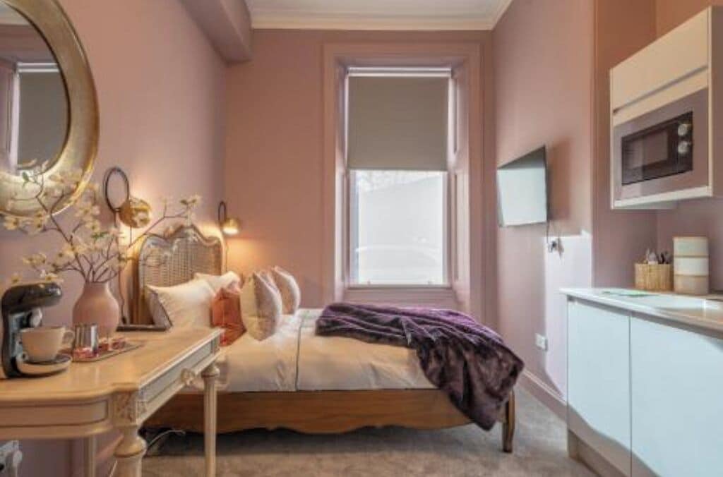 A bedroom with a bed, a dresser, a mirror, and a window.