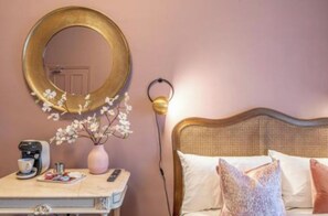 A bedroom with a bed, a bedside table with a coffee maker, a vase with flowers, and a wall-mounted mirror. - Boutique Home Stay (Paisley)