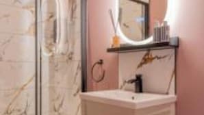 A bathroom with a marble shower, a white vanity, and a mirror with a light. - Boutique Home Stay (Paisley)