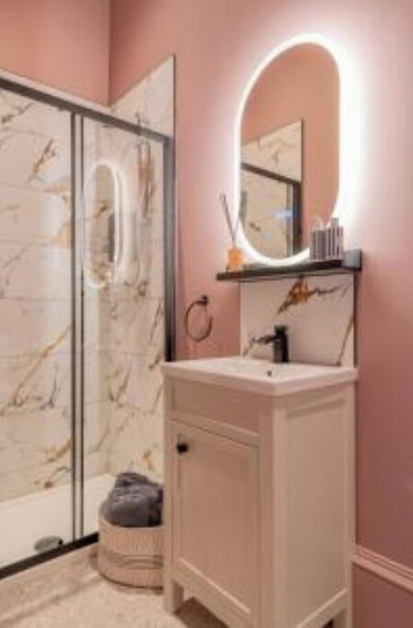 A bathroom with a marble shower, a white vanity, and a mirror with a light. - Boutique Home Stay (Paisley)