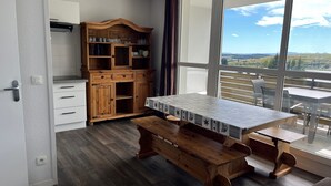 Una cocina moderna con armarios de madera, una mesa de comedor con mantel estampado y vistas amplias a través de grandes ventanales.