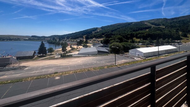 Vista de un lago con edificios y árboles al fondo.
