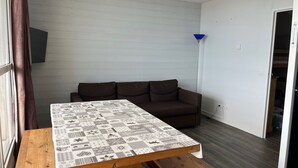 Una habitación con una mesa de madera, un sofá marrón y un mantel estampado.