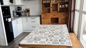 Una cocina con armarios blancos, un microondas, una cafetera y un mueble de madera con cristalería.