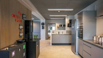 Una cocina moderna con electrodomésticos de acero inoxidable, una estación de café y un cubo de basura.