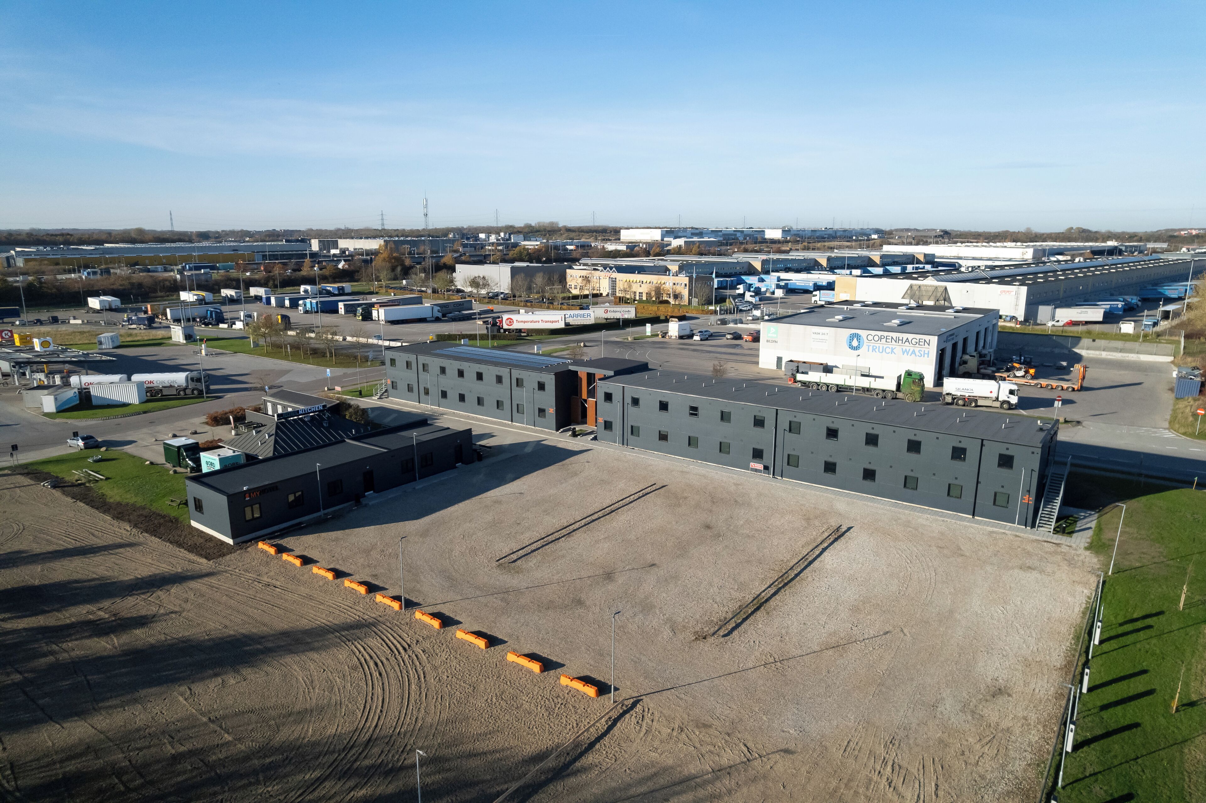 Zona industrial con un edificio grande que dice "Copenhagen Truck Wash" y varios camiones estacionados.