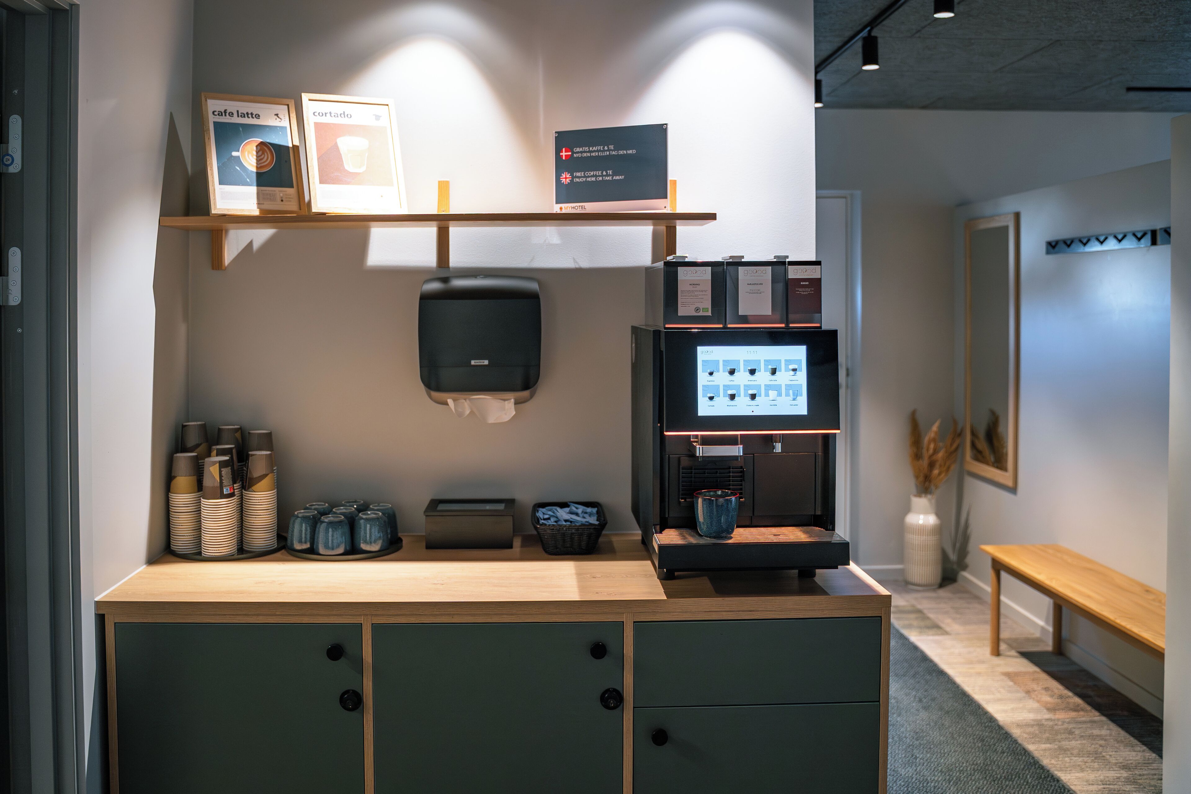 A coffee station with a coffee machine, cups, and a sign indicating free coffee.