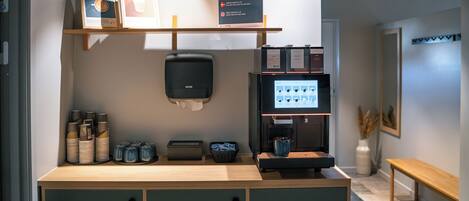 A coffee station with a coffee machine, cups, and a sign indicating free coffee.