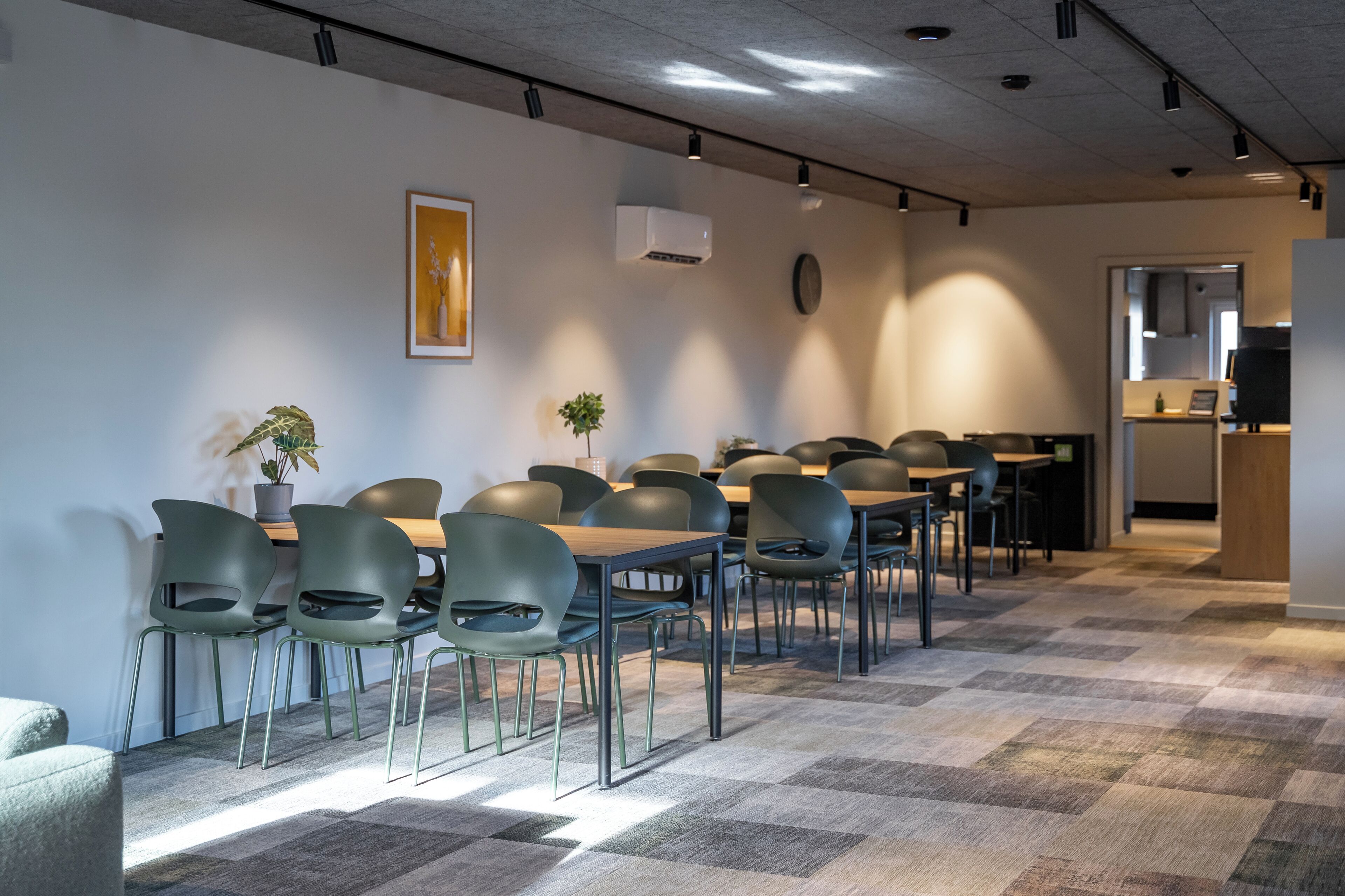 A modern conference room with a checkered floor, green chairs, and a wooden table.
