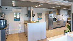 Une cuisine moderne dotée d’appareils électroménagers en acier inoxydable, d’un îlot central et offrant une vue sur le paysage urbain par une fenêtre.