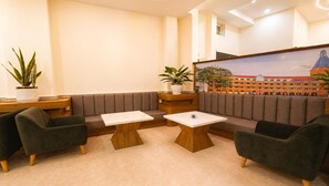 A modern lounge area with seating, a coffee table, and a large painting of a building. - Lien's 2 Hotel Da Lat (Da Lat)