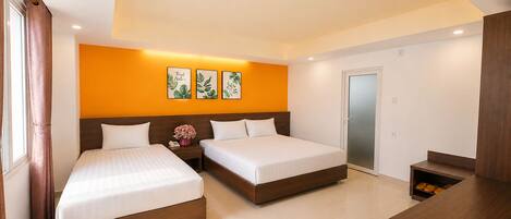 A hotel room with two beds, a nightstand with a phone and flowers, a wooden bench, and a sliding door.