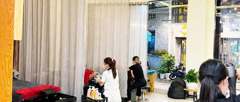 Un salón con un diseño moderno en el techo, un ventanal grande y una barra con herramientas de peluquería.