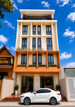 Un hôtel à la façade moderne, doté de nombreuses fenêtres, avec une voiture garée devant.